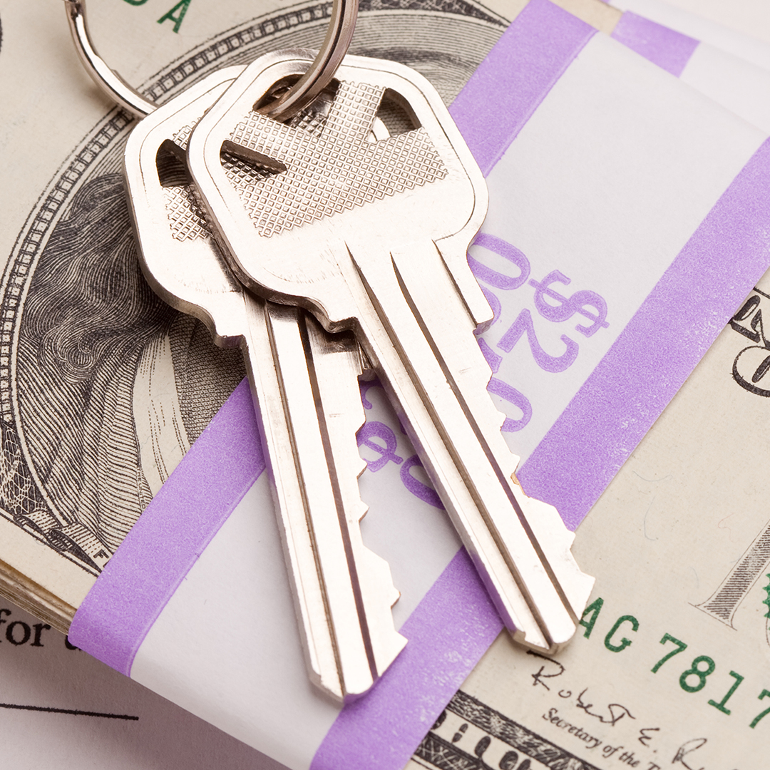 Image of a house keys sitting on a stack of cash