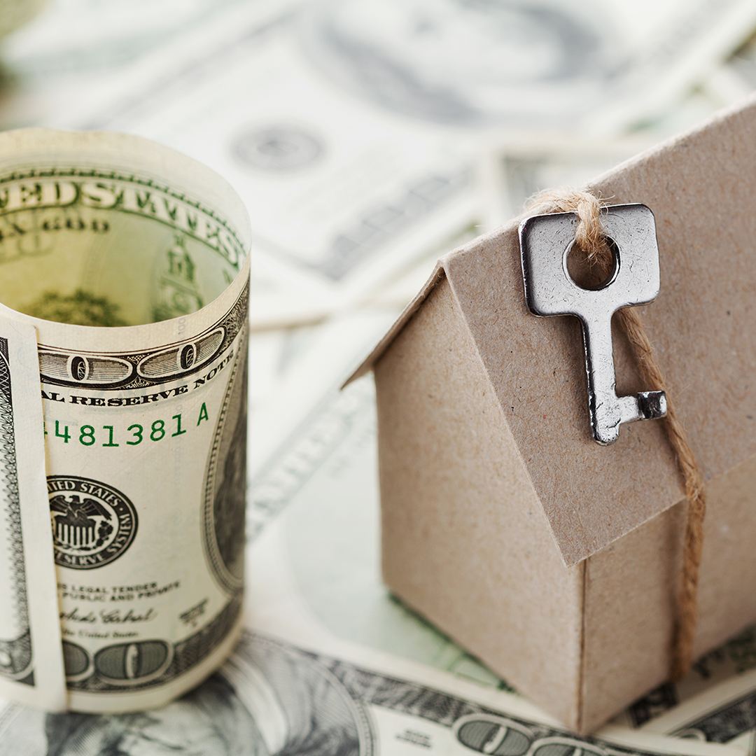 Image of money next to a cardboard house