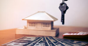 image of house keys over cash with a model house in the background
